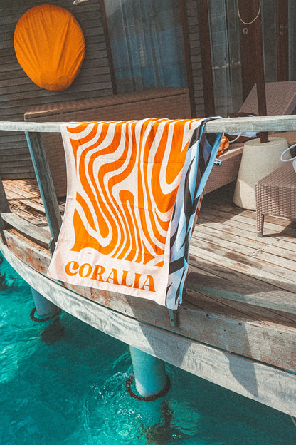Coralia & Co. Large Quick Dry Microfiber Beach Towel - Coral Waves side view with vibrant orange, white, black, and blue colors